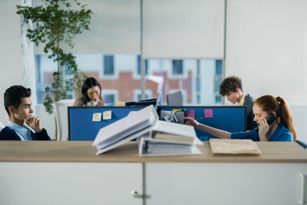 Contemporary office setting with diverse employees working diligently at their cubicles.